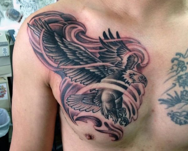 Tattoo of a flying eagle with outstretched wings on a person's chest and shoulder