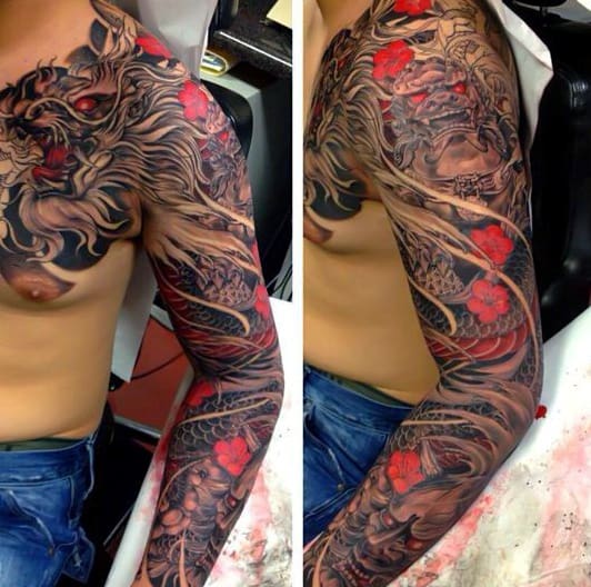 Japanese-style full sleeve and chest tattoo featuring a fierce dragon, intricate black and grey shading, and vibrant red cherry blossoms