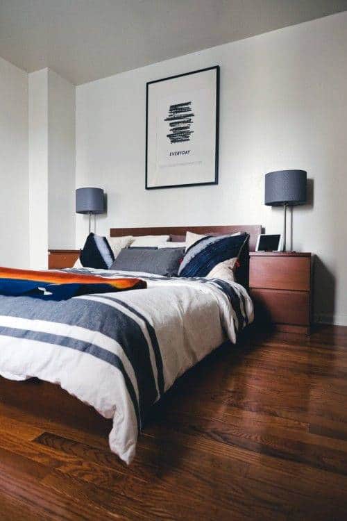 Modern bedroom with wooden floors, double bed, two side tables, and framed artwork