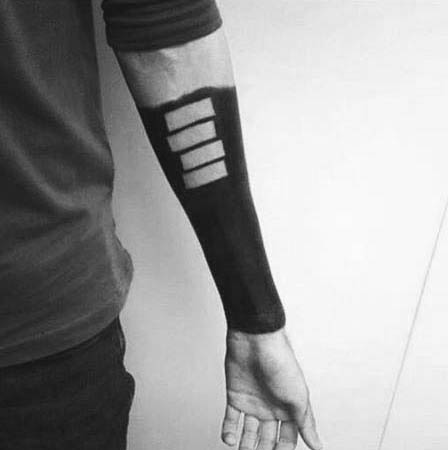 Negative space Black Flag bars set within a fully blacked-out forearm tattoo, creating a bold and striking punk silhouette.