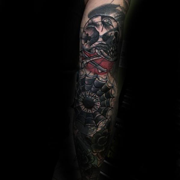 Blast over arm tattoo featuring a skull, roses, and a web on a dark backdrop