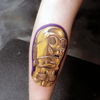 Hyper-realistic C-3PO tattoo with reflective gold detailing and a bold purple outline, creating a striking 3D effect on the skin.