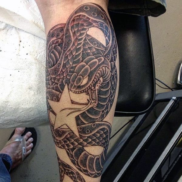 Black and grey calf tattoo of a coiled snake with intricate scales, wrapped around a bold five-pointed star
