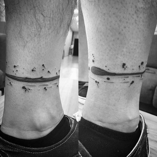 Alt text: Minimalist black ink tattoo of a canoe with splashes, wrapped around the ankle for a sleek and dynamic design.
