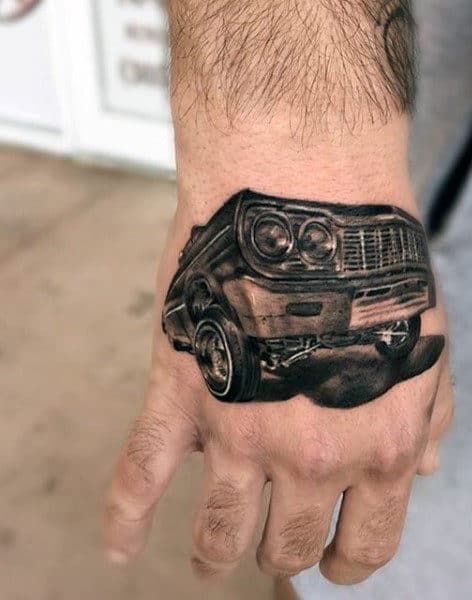 A realistic tattoo of a vintage car is inked on the back of a hand