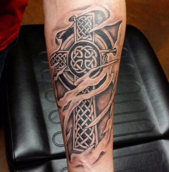 Forearm tattoo of a Celtic cross with intricate knot patterns and flowing ribbon details