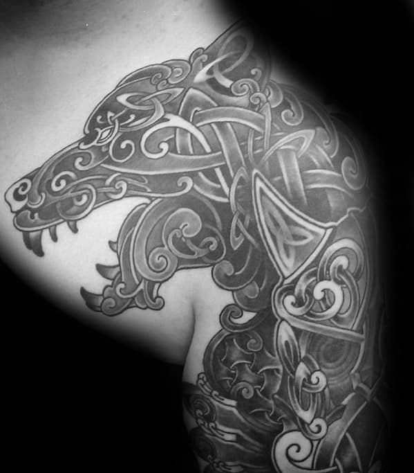 Celtic wolf tattoo on shoulder and upper arm with intricate knotwork forming two stylized wolves in a fierce, interwoven composition.