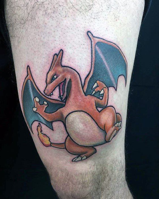 Classic Charizard tattoo on thigh with bold outlines, vivid orange shading, and a playful pose with wings spread and tail flame lit.