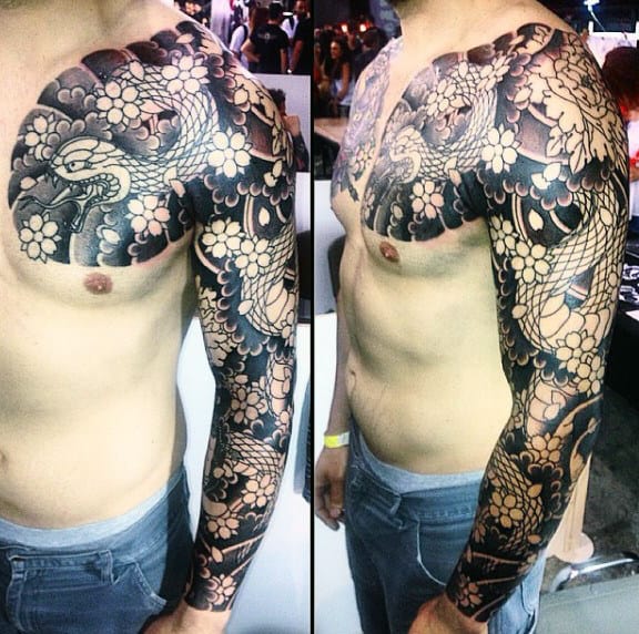 Man with detailed full sleeve and chest tattoo of a dragon and flowers