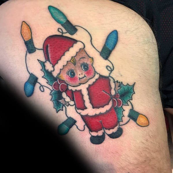 Christmas tattoo of a vintage-style Santa doll with rosy cheeks, surrounded by holly leaves and colorful holiday lights for a nostalgic festive design.