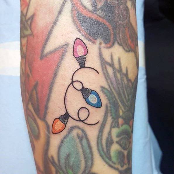 Minimalist Christmas tattoo of two interlocking circles with colorful holiday lights, blending a simple yet festive design with a creative twist.