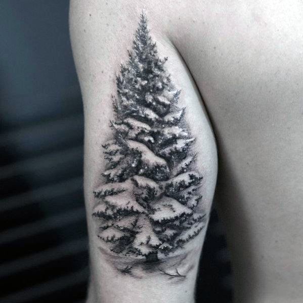 Realistic Christmas tree tattoo with intricate shading and snow-covered branches, creating a detailed and wintery design on the upper arm.