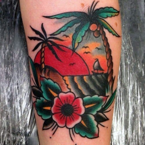 Bold traditional tattoo of a sunset beach scene with coconut palm trees, ocean waves, sailboat, and tropical flower on the forearm.