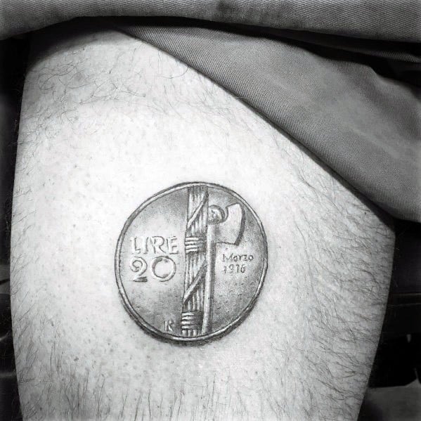 Realistic tattoo of a 20 Lire Italian coin on the thigh, featuring fine shading and intricate details for a three-dimensional effect.