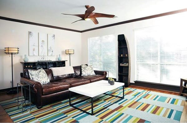 Colorful bachelor pad living room with striped rug, leather sofa, and modern decor accents.