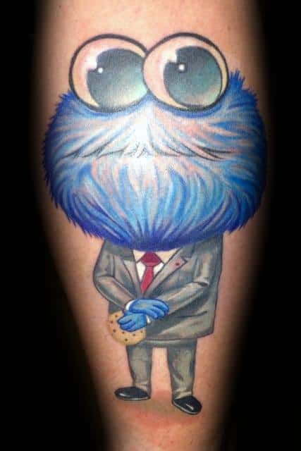 Cookie Monster tattoo with oversized eyes, dressed in a gray suit and red tie, calmly holding a cookie in both hands.
