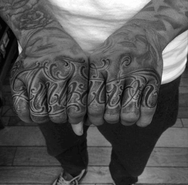 Ambitious hands showcase "Ambition" tattooed across the knuckles in bold black ink