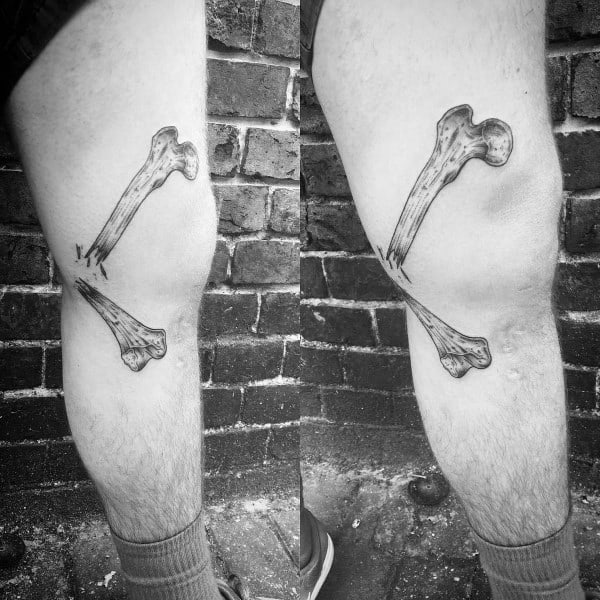 Black and grey tattoo of two crossed femur bones on the back of the leg, designed with realistic bone texture and shading.