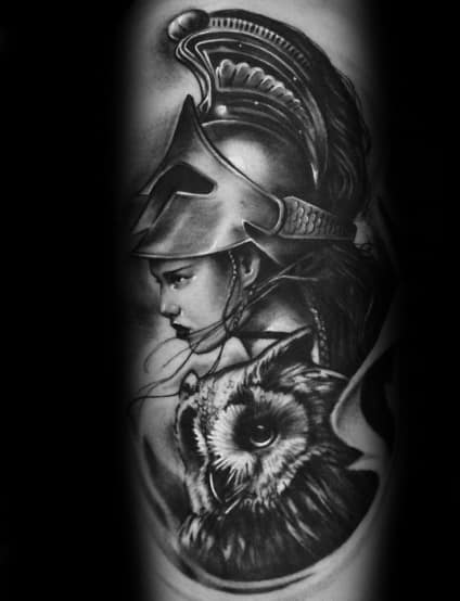 Athena tattoo with intense side-profile, detailed plumed helmet, and a realistic owl below in black and grey realism on upper arm