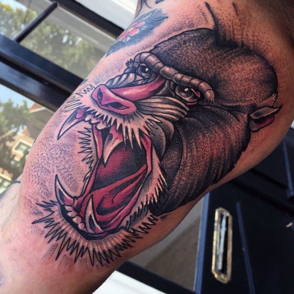 Detailed baboon tattoo with bold linework, intense shading, and a fierce open-mouthed expression, creating a striking and dynamic arm design.