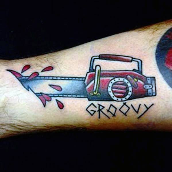 Cartoon-style tattoo of a red chainsaw with blood splatter and the word "GROOVY" in stylized lettering beneath the blade.