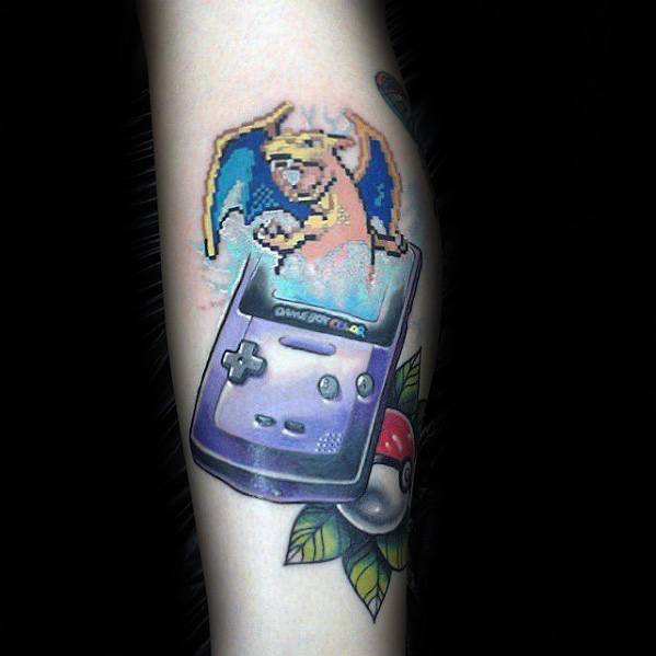 Colorful tattoo of a Game Boy Color with pixelated Charizard emerging from the screen, paired with a Poké Ball and leaf details.
