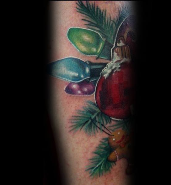 Christmas tattoo featuring colorful holiday lights, a red ornament, pine branches, and a gingerbread cookie for a festive and detailed holiday design.