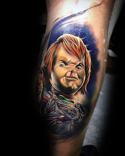 Realistic Chucky tattoo with bold colors, featuring his intense expression, piercing eyes, and a raised knife for a striking horror-inspired design.