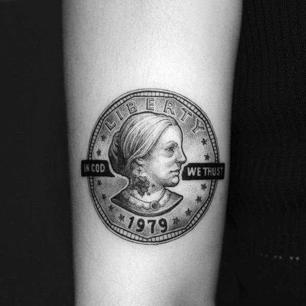 Realistic tattoo of a 1979 Liberty coin with a custom portrait, featuring intricate shading and bold 'In God We Trust' lettering.