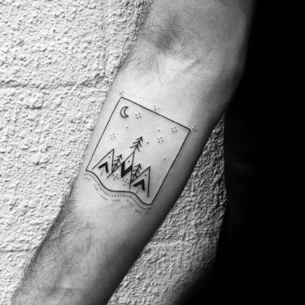 Forearm tattoo of mountains, a tree, dots, and a crescent moon inside a square frame