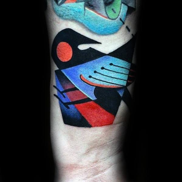 Cubist-style bird tattoo on the forearm with bold black outlines and vibrant blocks of red, blue, and purple in a geometric layout.