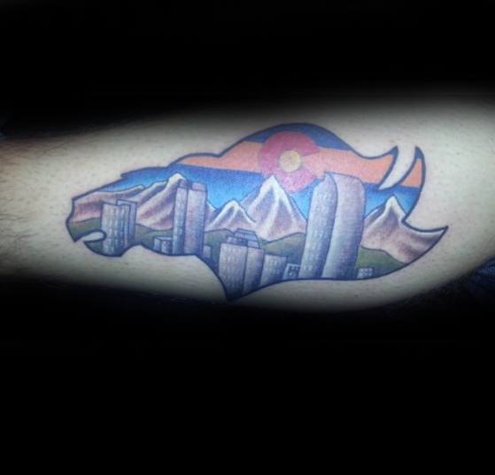 Colorful Denver skyline and mountain tattoo shaped like a buffalo, featuring the Colorado flag sunset and city buildings inside the silhouette.