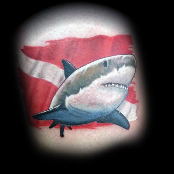 Tattoo of a great white shark in front of a red and white dive flag, symbolizing a passion for scuba diving and respect for marine predators.