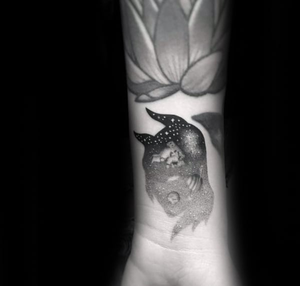 Black and grey tattoo of a dreamy horned figure filled with stars, planets, and a sleeping child, blending cosmic elements with innocence.