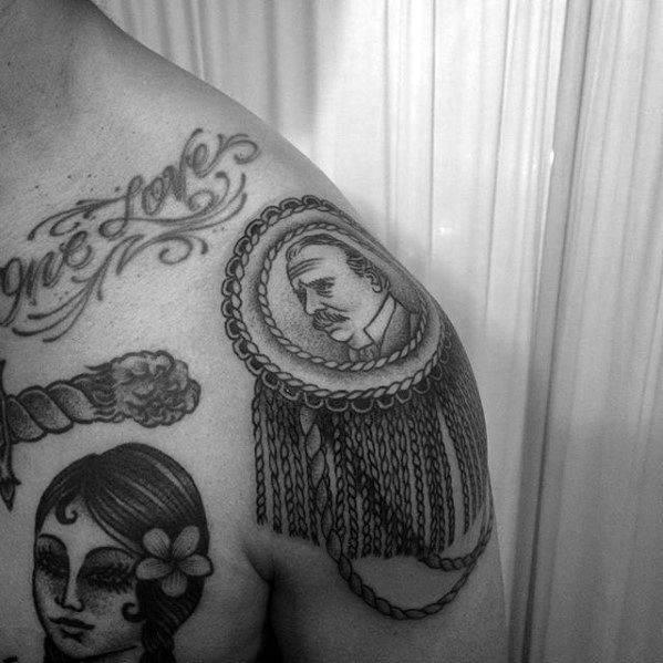 Epaulette tattoo with a vintage portrait centerpiece, detailed rope and tassel design flowing over the upper arm.