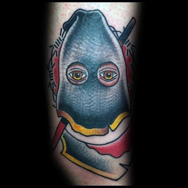 Bold executioner tattoo featuring a hooded figure with piercing eyes, a bloodied axe, and barbed wire detailing in a neo-traditional style.