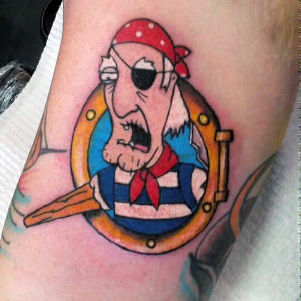 Tattoo of Seamus from Family Guy, the peg-legged and peg-armed pirate, wearing a red bandana and eyepatch, emerging from a ship’s porthole.