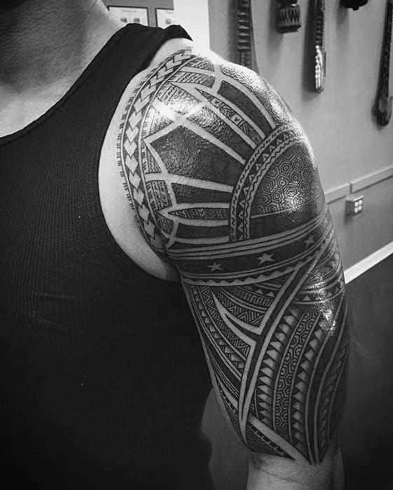 Filipino sun tattoo on the shoulder with intricate tribal rays, detailed geometric textures, and star accents forming a bold half-sleeve design.