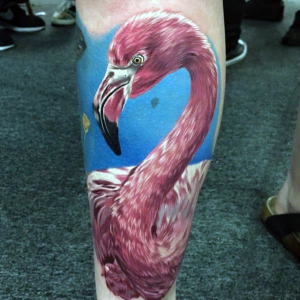 Hyper-realistic flamingo tattoo with detailed pink feathers and a vivid blue background, creating a lifelike and eye-catching design.