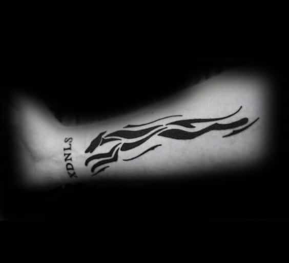 A dynamic and bold tattoo of a greyhound in motion, using fluid, abstract lines that convey speed and agility, with the word "STNLS" beneath it.