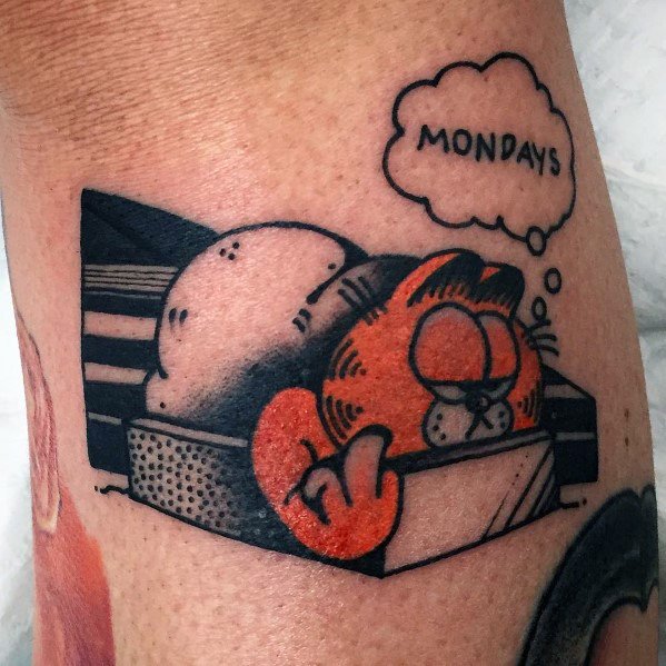 Garfield tattoo sleeping in a shoebox with a 'Mondays' thought bubble—bold black and orange design capturing his lazy attitude.
