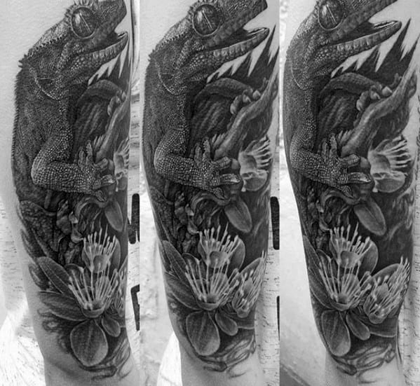 Hyper-realistic black and grey gecko tattoo sleeve with intense texture, sharp details, and layered flowers surrounding the reptile.