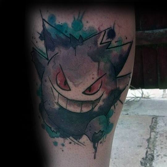 Dark watercolor-style Gengar tattoo with splashes of teal and black ink, featuring a sinister grin and haunting red eyes.