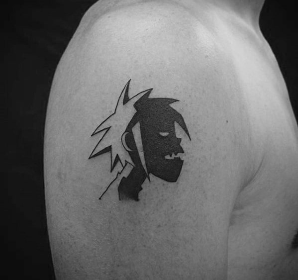 Minimalist black silhouette tattoo of 2D from Gorillaz on the upper arm, featuring his spiky hair and distinct side-profile expression.