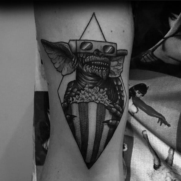 Black and gray Gremlin tattoo with 3D glasses, sharp teeth, and a popcorn bucket, blending horror and cinema nostalgia in a bold design.