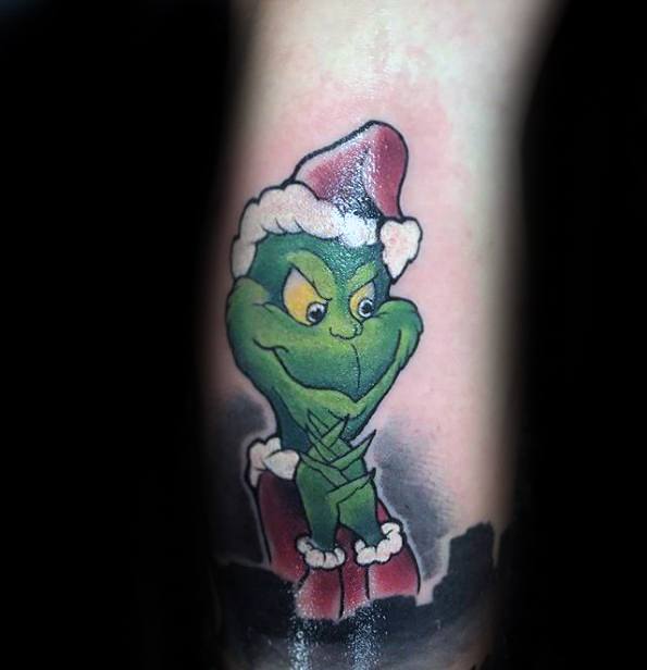 Grinch wearing a Santa hat, with a mischievous expression and vibrant green coloring, in a playful tattoo design with bright details and bold shading.