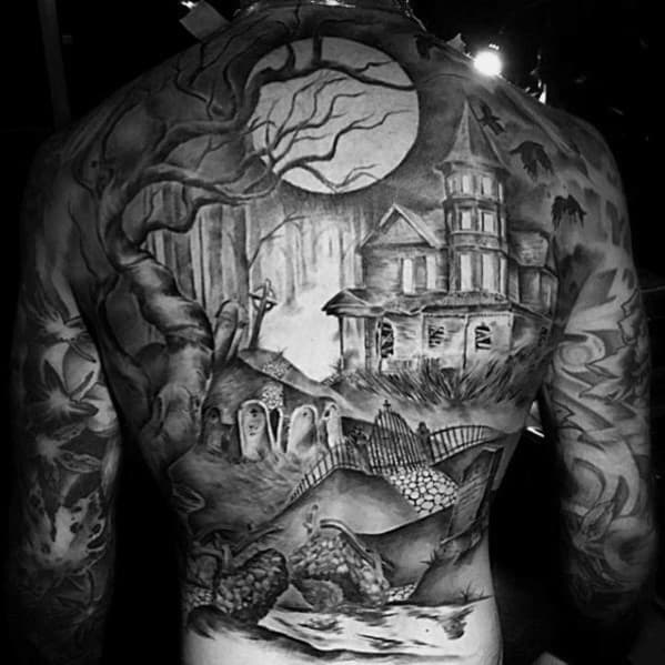 Full back tattoo of a haunted house with a glowing full moon, eerie graveyard, twisted trees, foggy woods, and spirits rising from tombstones.