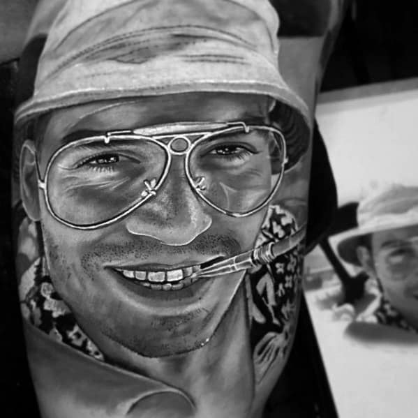 Black and white Hunter S. Thompson tattoo featuring a highly detailed, realistic portrait with aviator glasses, a bucket hat, a cigarette, and a wide smile.