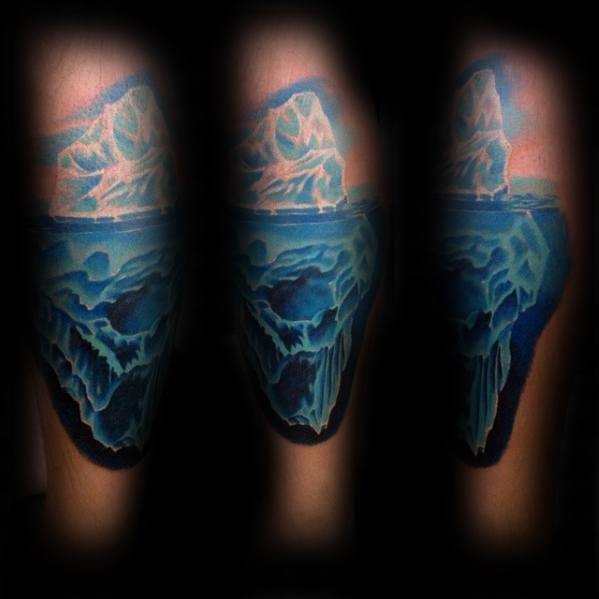 Realistic full-color iceberg tattoo with deep blue tones, wrapping around the arm to show the massive submerged structure in 3D detail.