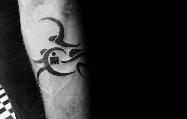 Ironman logo tattoo integrated into a tribal design, with flowing lines representing movement in the disciplines of swimming, biking, and running.